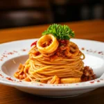 A plate of spaghetti with seafood and a sprig of parsley sits on a wooden table.